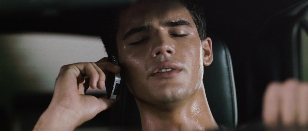 Caleb (Steven Strait) talking on his phone at the steering wheel of his car, drenched in sweat.