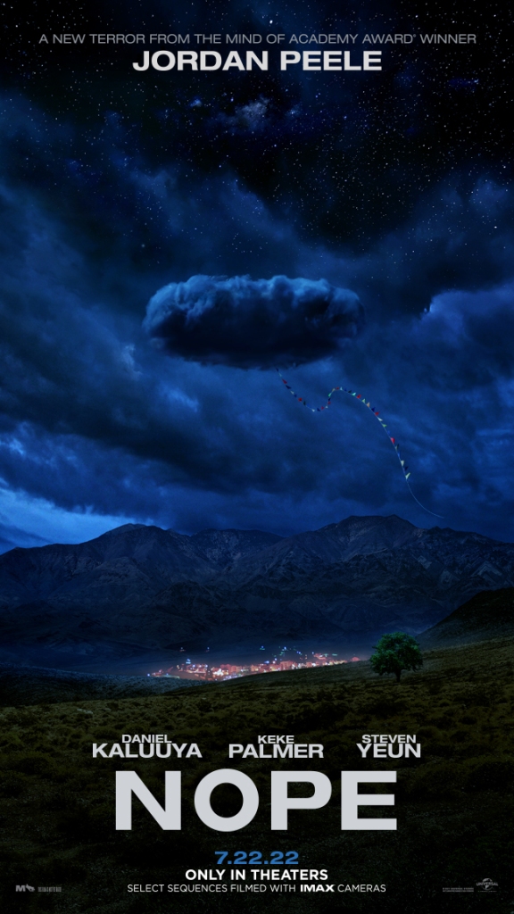 The film poster showing a cloud trailing a line of little flags, over an illuminated Western village in the middle of nowhere.